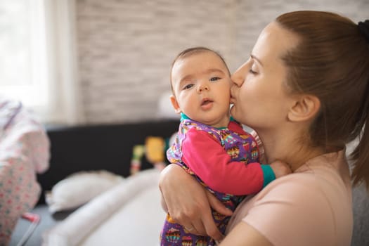 A mother shares a tender moment with her baby at home.