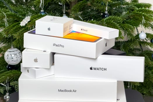 BERLIN , GERMANY - JANUARY 14 2024: Pyramides of boxes with air pods, Apple watch, Macbook Pro, Macbook Air, iPad pro and iphone under Christmas tree.