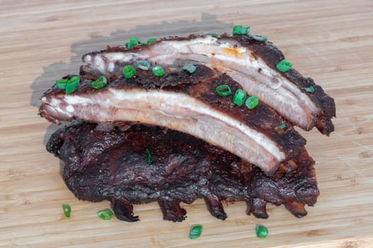 Indulge in succulent grilled BBQ ribs adorned with fresh green onions, an ideal dish for any enthusiastic meat lover