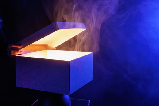 human hands taking out surprise from mysterious box on dark red background surrounded by smoke, mystery box