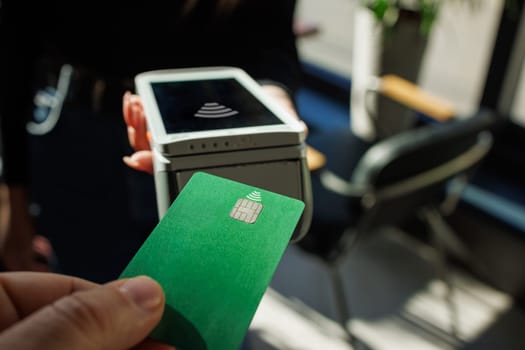 Close Up of a Masculine Hand Holding a Credit Card with an NFC Payment Technology Used for Paying . Customer Uses Debit Card to Pay Through Bank Terminal.