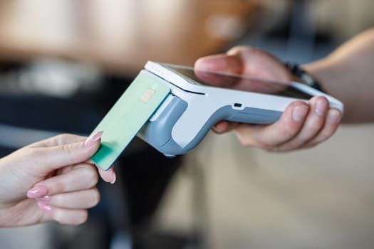 Customer paying with credit card using POS machine indoors, closeup, Customer Uses Debit Card to Pay Through Bank Terminal