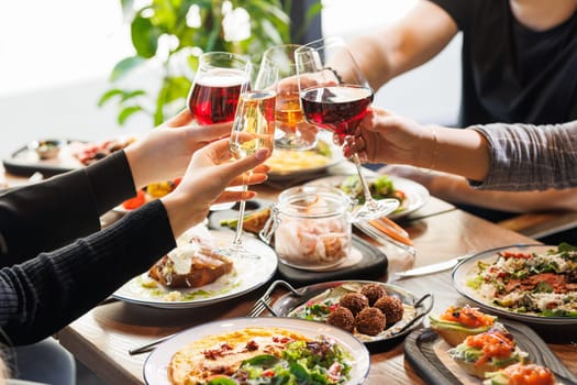 Friends Gathering Together at a Cafe Terrace in the Evening. Diverse Young People Raising, Toasting and Clinking Glasses with Wine and Champagne, Celebrating Their Reunion