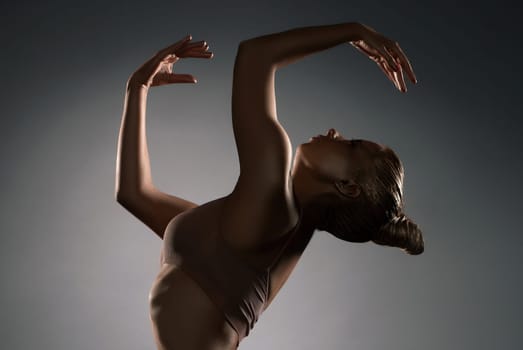 Graceful girl in ligerie with gold bodyart profile shot in the dark room