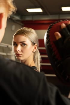 Pretty girl and man in boxing gloves in boxing ring close up view