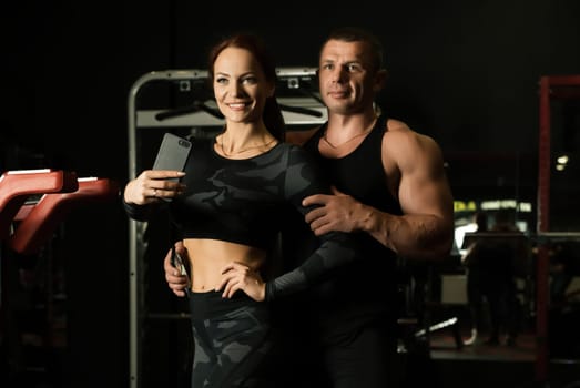 Male athlete and slim fitness trainer exercising on simulator view in sports gym