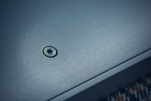 A detailed and closeup view of a single screw that is deeply embedded into a smoothly polished metallic surface