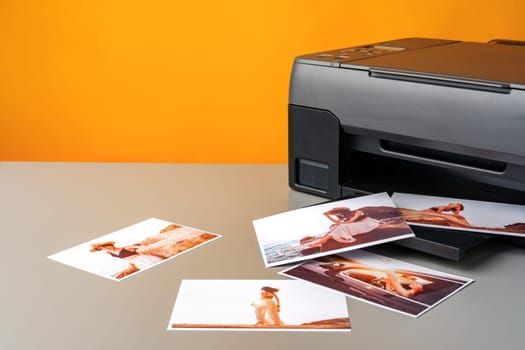 Printer printing colorful photos of people close up, yellow background, studio shot