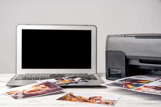 Computer laptop and printer on the table. Printing photos