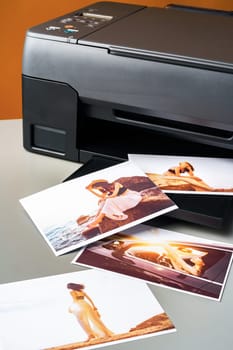 Modern laser printer printing color photos of women close up on desk