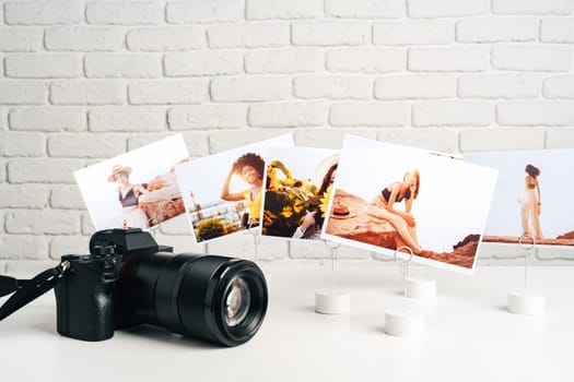 Camera and colorful printed photos of women on the desk close up