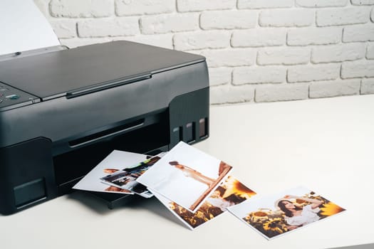 Modern laser printer printing color photos of women close up on desk