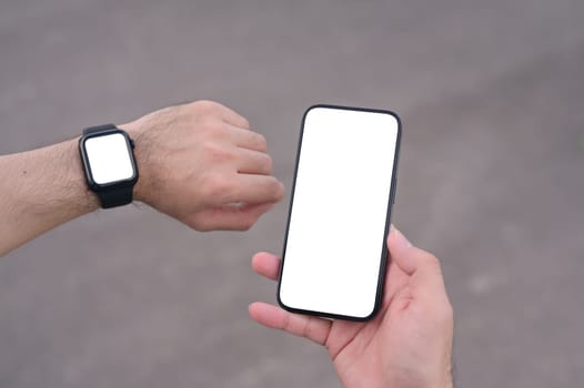 Athlete man checking workout stats on his phone and smartwatch.