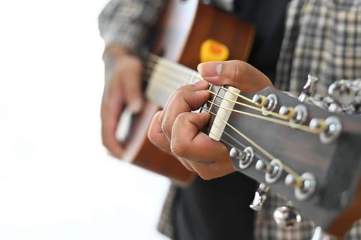 Man in plaid shirt playing an acoustic guitar on sofa at home. Leisure, hobby and activity concept.