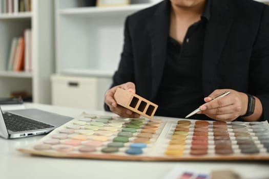 Interior designer analyzing color palettes and material samples for home project at office.