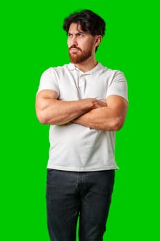 A man with a serious expression stands with crossed arms against a vibrant green background close up