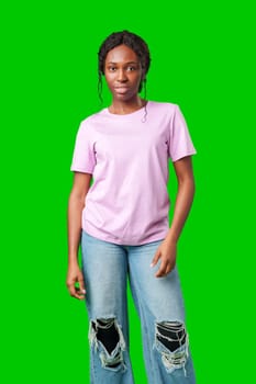 A joyful young woman smiling brightly while standing against a vivid green background in studio
