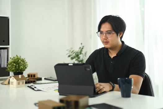Interior designer reviewing project details and using digital tablet at modern office.