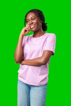 Happy young person laughing and playfully covering face while standing against a bright green background in studio