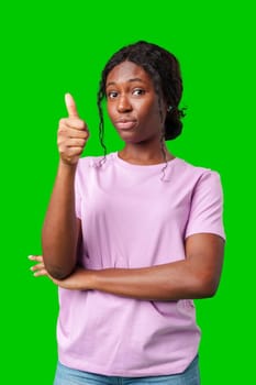 Young adult giving a thumbs up with a confident expression against a vibrant green background close up