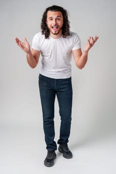 Young man with curly hair expresses surprise in a light-colored setting close up