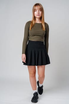 A young woman with straight hair wearing a green top poses against a neutral background in a calm setting