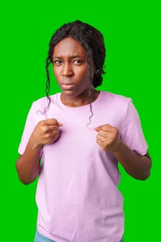 A surprised woman poses dramatically with hands on her chest in front of a bright green background in studio
