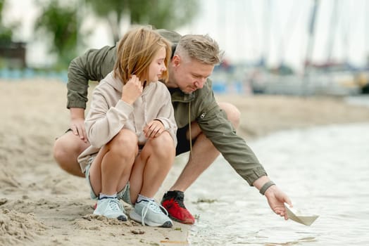 Dad And Daughter Launch Paper Boat In River