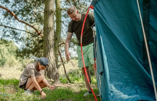 Father And Daughter Setting Up A Tent While Camping In The Forest