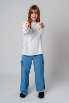 A young girl in a white sweatshirt playfully poses with finger guns against a neutral background close up
