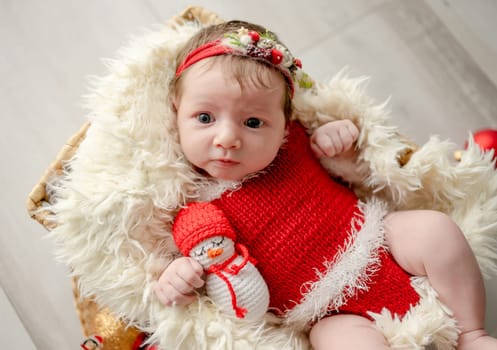 Newborn baby girl wearing Santa Christmas costume sleeping in basket with xmas decoration. Little infant child New Year portrait