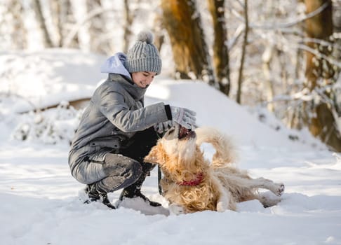 Teenage Girl Plays With Golden Retriever In Snowy Forest, Sitting With Dog