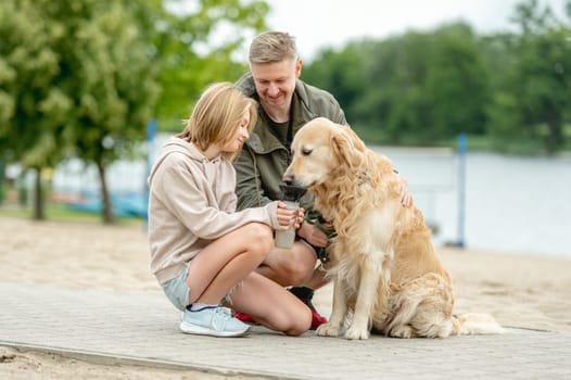 Girl With Dad Gives Golden Retriever A Drink While On A Walk