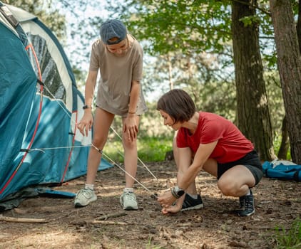 Mother And Daughter Setting Up A Tent In The Forest For The Summer