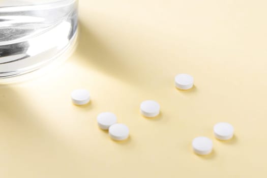 Tablets on the table next to a glass of water. Supporting the body with vitamins and dietary supplements.