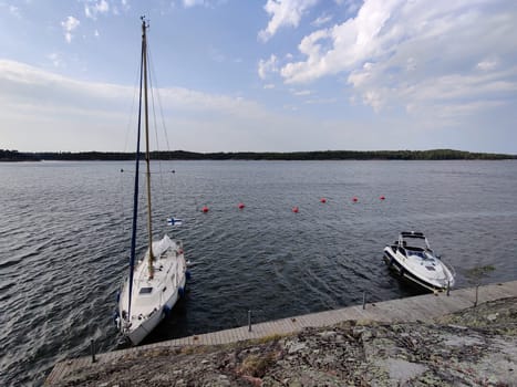 Sailboat tied to a mooring buoy at the harbor of the island in Finland, Baltic sea, Yacht in Shore marina in Baltic Sea, a safe anchorage for yachts and sail boats.