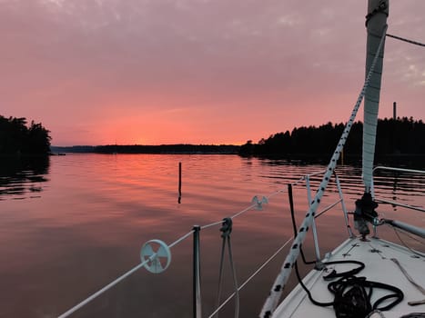 View from the bow of a sailing yacht on a beautiful red sunset in the Baltic Sea, Finland