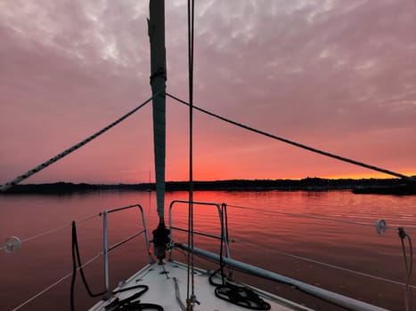 View from the bow of a sailing yacht on a beautiful red sunset in the Baltic sea