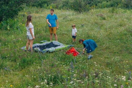 A happy family enjoys an adventurous camping trip, setting up their tent in a lush green field with flowers