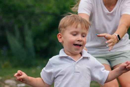 A cheerful young boy runs joyfully outdoors, with a loving parent nearby, capturing a moment of happiness.