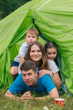 A joyful family is happily enjoying quality time together inside a bright and vibrant green camping tent