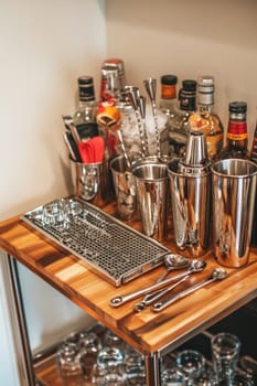 Stainless steel cocktail shaker and bar tools sitting on a bar cart waiting for a bartender to make a drink