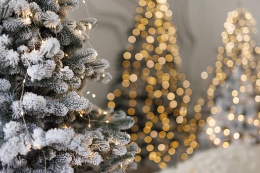 snowy fir tree close-up with garland and blurred lights in the background. New Year and Christmas celebration concept