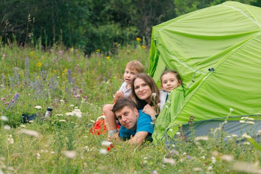 A joyful family is happily enjoying a delightful camping experience in a vibrant flowerfilled meadow area