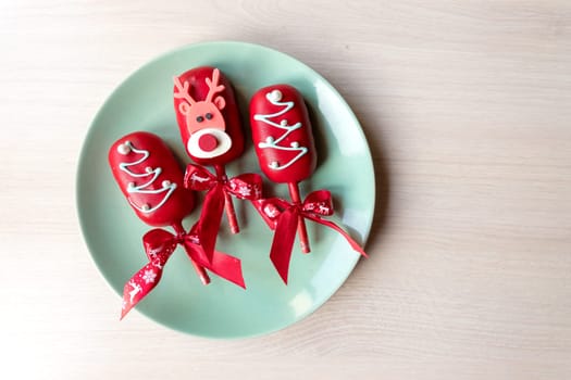Flat lay of cake pops ice cream on a stick in pink glaze with strawberries and blueberries on a light background.