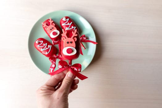 Flat lay of cake pops ice cream on a stick in pink glaze with strawberries and blueberries on a light background.