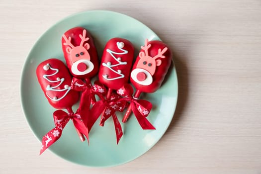 Flat lay of cake pops ice cream on a stick in pink glaze with strawberries and blueberries on a light background.