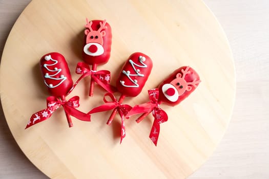 Flat lay of cake pops ice cream on a stick in pink glaze with strawberries and blueberries on a light background.