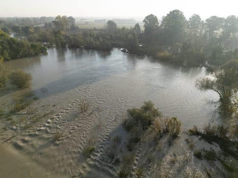 Castelvetro Piacentino. Italy - October 21st 2024 Muddy water is flooding the fields next to a river after heavy rain, damaging the vegetation putting the environment at risk caused by climate change