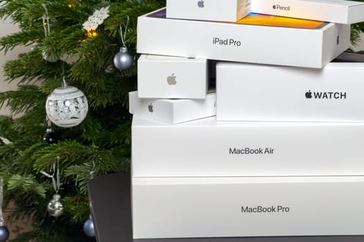 BERLIN , GERMANY - JANUARY 14 2024: Macbook pro, air, apple watch. iphone, ipad pro boxes under Christmas tree.